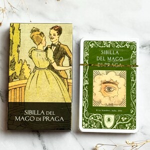 以下が含まれることがあります： タロットカードのデッキとその箱。箱には、踊るカップルのイラストと「SIBILLA DEL MAGO DI PRAGA」の文字が描かれています。カードデッキは、緑色の縁取りに「SIBILLA DEL MAGO DI PRAGA」の文字と目のイラストが描かれています。