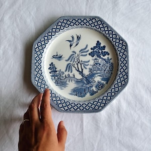 May include: A blue and white octagonal ceramic plate with a blue and white willow pattern. The plate has a decorative border of blue and white diamonds.