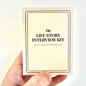 Op de afbeelding: Een witte doos met zwarte tekst die "The Life Story Interview Kit" en "Questions to capture your family's unique legacy" zegt.