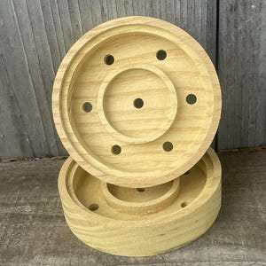 May include: Two wooden round candle holders with holes for air flow. The holders are stacked on top of each other.