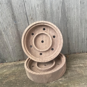 May include: Two wooden circular coasters with a ring of holes around the edge and a smaller ring of holes in the center. The coasters are stacked on top of each other.