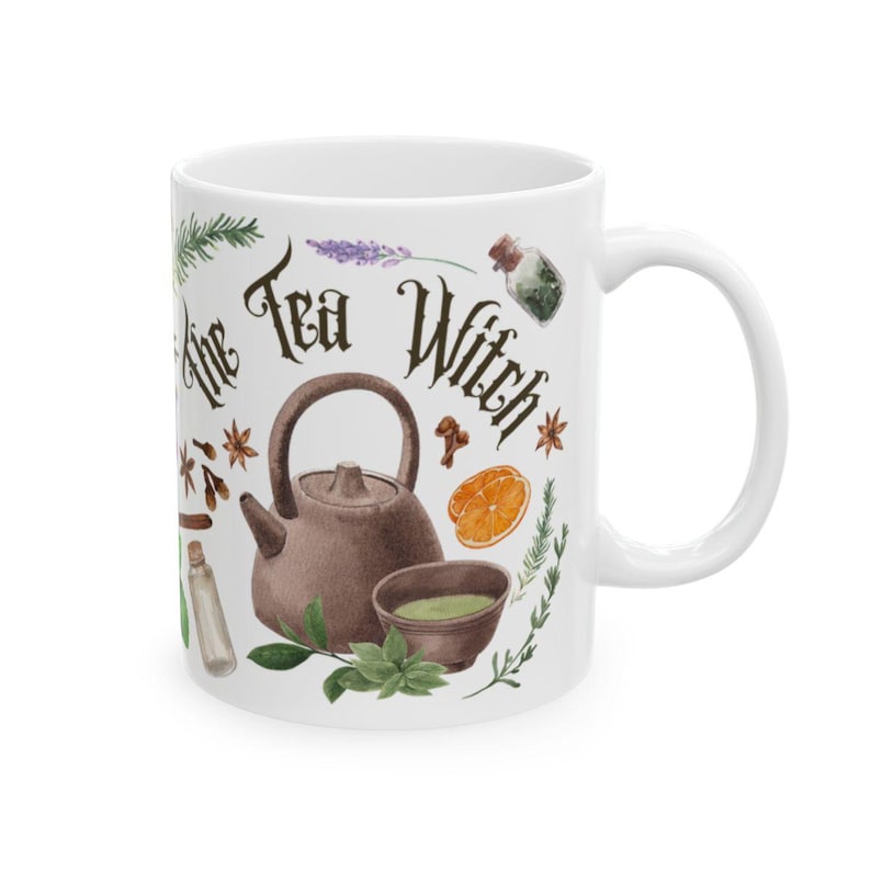 May include: White ceramic mug with a brown teapot, green teacup, and various herbs and spices. The text "The Tea Witch" is printed in black on the mug.