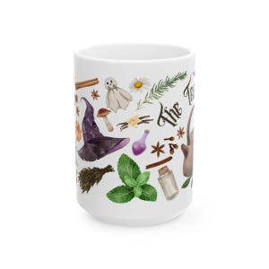 May include: White ceramic mug with a whimsical design featuring a witch's hat, a ghost, herbs, and the text "The Forest"