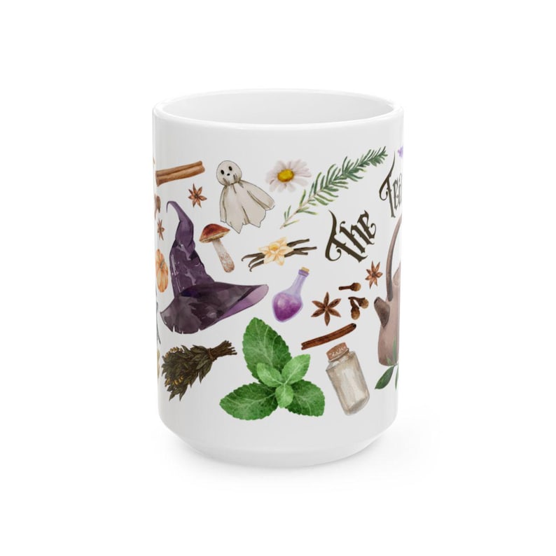 May include: White ceramic mug with a whimsical design featuring a witch's hat, a ghost, herbs, and the text "The Forest"