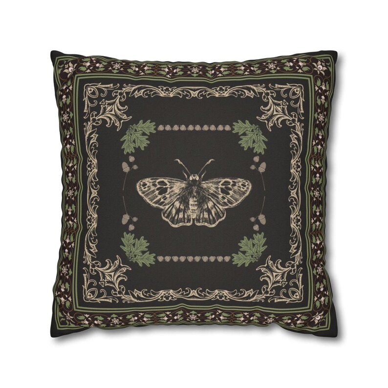 May include: A black throw pillow with a decorative border and a vintage illustration of a butterfly in the center. The butterfly is surrounded by a wreath of green leaves and brown berries.