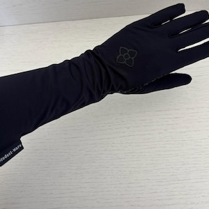 May include: Black gloves with a long sleeve design. The gloves have a floral emblem on the back of the hand and the text "Modest-ware" on the cuff. The gloves are made of a smooth, dark fabric.