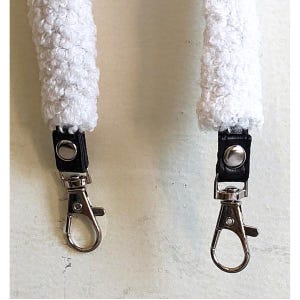 May include: A white textured sherpa strap featuring black leather tabs and silver-toned metal swivel lobster clasps. The strap has a thick, curly fleece-like surface texture and is secured to the metal hardware with silver-colored rivets.