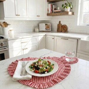 Puede incluir: Una ensalada fresca en un plato blanco, colocada sobre un mantel individual de cuadros rojos y blancos con borde con volantes. Un posavasos a juego y un vaso de agua est&aacute;n cerca. Una servilleta blanca y cubiertos completan el conjunto.