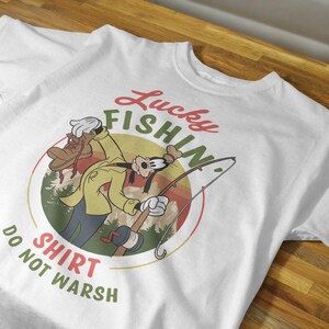 May include: White t-shirt with a cartoon image of Goofy fishing. The text "Lucky Fishin' Shirt Do Not Wash" is printed on the shirt.
