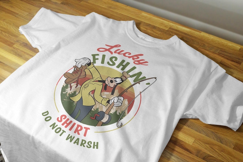 May include: White t-shirt with a cartoon image of Goofy fishing. The text "Lucky Fishin' Shirt Do Not Wash" is printed on the shirt.