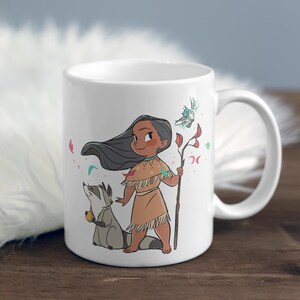 May include: White ceramic mug with a cartoon illustration of a Native American girl with long black hair, wearing a brown dress and holding a stick with a bird on it. A raccoon is standing next to her. The mug has a white handle.