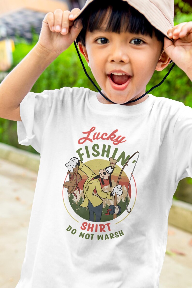 May include: White t-shirt with a cartoon image of Goofy fishing. The image is in a circle with the text "Lucky Fishin' Shirt Do Not Wash" below it.