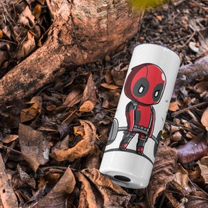 May include: White travel mug featuring a red and black cartoon character lifting weights. The character has a red mask and a black and red suit. The text "Deadpool" is not visible in the image.