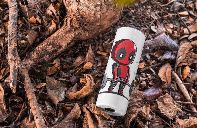 May include: White travel mug featuring a red and black cartoon character lifting weights. The character has a red mask and a black and red suit. The text "Deadpool" is not visible in the image.