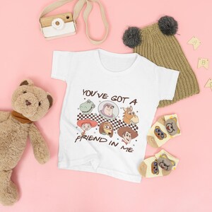 Op de afbeelding: Witte baby romper met een afbeelding van Toy Story-personages en de tekst "You've got a friend in me".