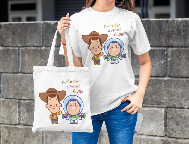 May include: White tote bag with a cartoon image of Woody and Buzz Lightyear from Toy Story. The bag has the text "You've Got a Friend in Me" printed on it.