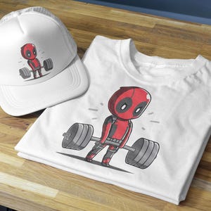 May include: White t-shirt featuring a cartoon image of Deadpool lifting weights. The t-shirt is folded and displayed next to a white mesh baseball cap with a similar image of Deadpool lifting weights.