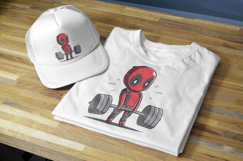 May include: White t-shirt featuring a cartoon image of Deadpool lifting weights. The t-shirt is folded and displayed next to a white mesh baseball cap with a similar image of Deadpool lifting weights.