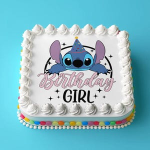 Op de afbeelding: Een witte cake met blauwe frosting en een blauw cartoonfiguur met een feestmuts. De cake is versierd met de woorden "Birthday Girl" in roze en zwart.