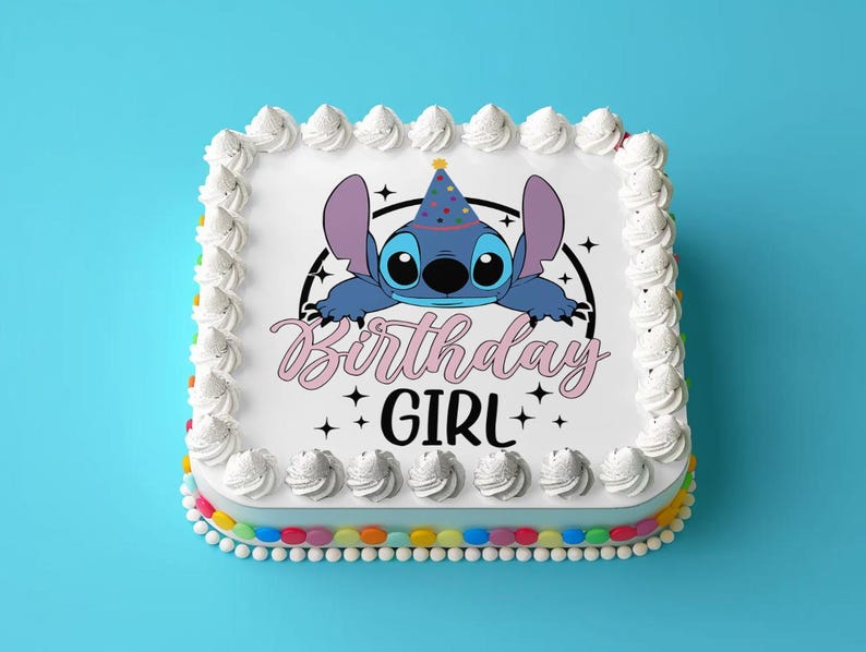 Op de afbeelding: Een witte cake met blauwe frosting en een blauw cartoonfiguur met een feestmuts. De cake is versierd met de woorden "Birthday Girl" in roze en zwart.