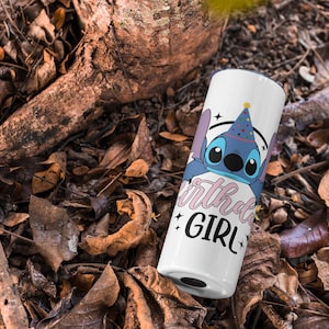 Op de afbeelding: Een witte tumbler met een blauw cartoonfiguur dat een feestmuts draagt. De tekst "Birthday Girl" staat in roze op de tumbler.