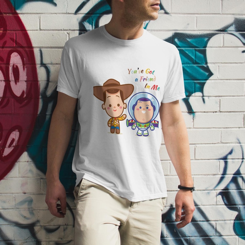 May include: White t-shirt with a cartoon image of Woody and Buzz Lightyear from Toy Story. The text "You've Got a Friend in Me" is printed on the shirt.