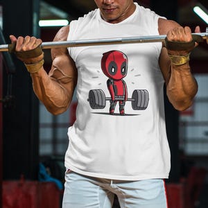 May include: A white vest top featuring a cartoon image of a red and black superhero lifting a barbell. The superhero is wearing a mask and has a red and black suit.
