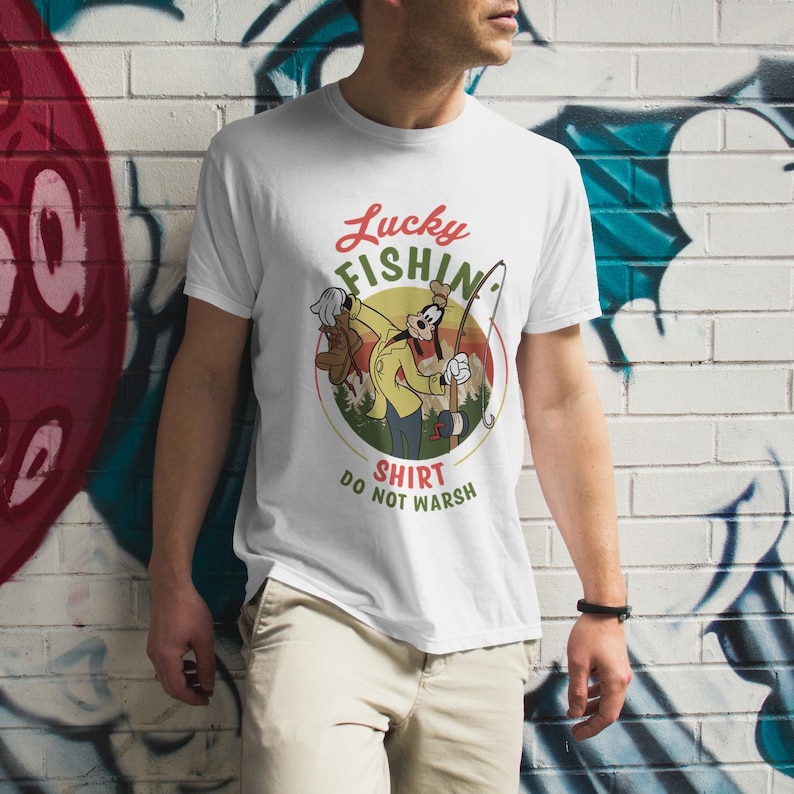 May include: White t-shirt with a cartoon image of Goofy fishing. The text "Lucky Fishin' Shirt Do Not Wash" is printed on the shirt.