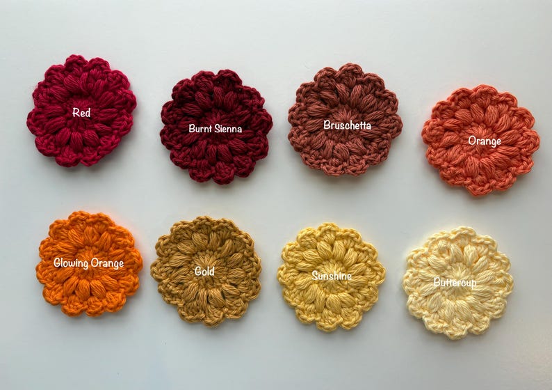 May include: Eight circular crochet flower appliques arranged in two rows. The colors are labeled as Red, Burnt Sienna, Bruschetta, Orange, Glowing Orange, Gold, Sunshine, and Buttercup. Each piece features a textured, puff-stitch petal design.