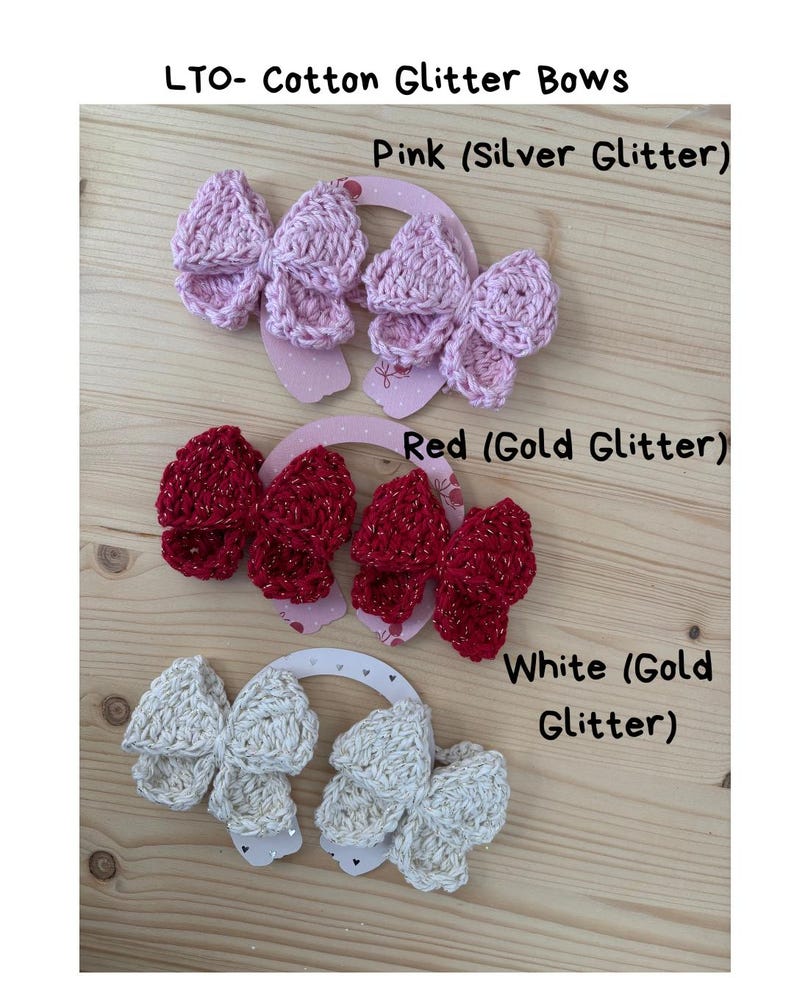 May include: Cotton glitter bows in pink, red, and white. The pink bows have silver glitter, the red bows have gold glitter, and the white bows have gold glitter. Each bow is attached to a decorative card.
