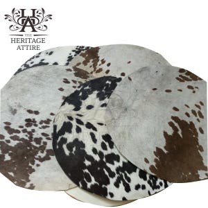 May include: A collection of cowhide rugs in various sizes and patterns. The rugs feature a mix of white, brown, and black spots and patches. The Heritage Attire logo is in the upper left corner.