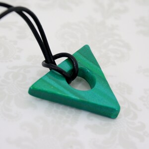 May include: A green triangle pendant with a hole in the center, hanging from a black cord.