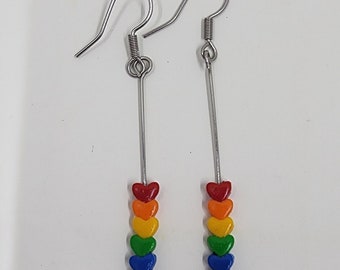 Könnte beinhalten: Regenbogen-Herz-Ohrringe mit silbernen Haken. Jeder Ohrring hat sechs Herzen in den Farben des Regenbogens.