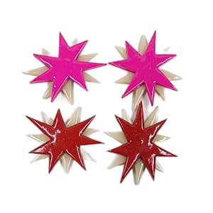 Pu&ograve; includere: Un paio di orecchini con due stelle rosa e due stelle rosse. Ogni stella ha un design a strati con una stella pi&ugrave; piccola sopra una stella pi&ugrave; grande.
