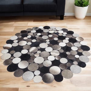May include: A round, gray and black cowhide rug made of stitched together circles of leather.