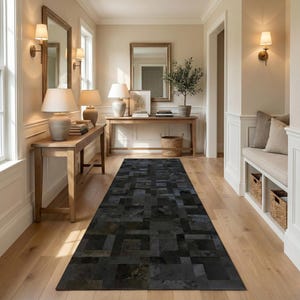Könnte beinhalten: Ein Flur mit einem rechteckigen, schwarzen Teppich aus geometrischen Formen. Der Teppich liegt auf einem hellen Holzboden. Auf beiden Seiten des Flurs befinden sich Holztische mit Lampen und Spiegeln. Die Wände sind neutral gestrichen.