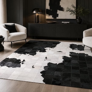 May include: A rectangular area rug featuring a patchwork design of cowhide squares in contrasting black and white tones. The rug displays a mix of solid black, solid white, and mottled black and white patches arranged in a grid-like pattern.