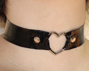May include: A black patent leather choker with a silver heart-shaped accent.