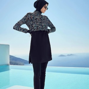 May include: A black and teal patterned swimsuit with long sleeves and pants. The swimsuit has a black skirt overlay with a drawstring waist. The model is wearing sunglasses and a black headscarf.