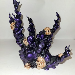 May include: A purple and black resin sculpture of a swirling, smoky cloud with multiple skulls embedded in it.