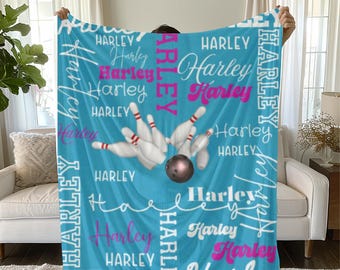 May include: A light blue fleece blanket featuring the name "Harley" in white and pink script. The blanket has a bowling theme, with a bowling ball and pins in the center.