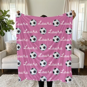 May include: Pink fleece blanket with a white football pattern and the name "Laura" repeated throughout.