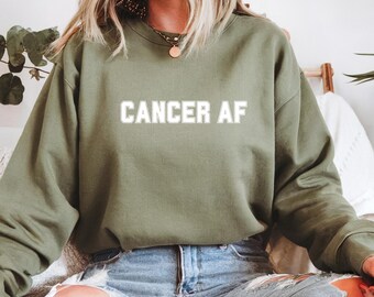 May include: A green sweatshirt with the text "CANCER AF" printed in white on the front.