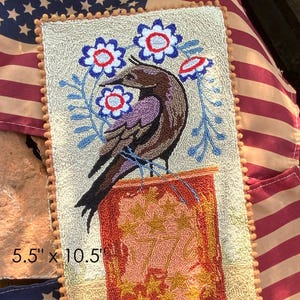 May include: A rectangular punch needle pattern featuring a crow perched on a red jar with gold stars. The design includes blue and red flowers and is 5.5" x 10.5". The text "1776 Redware Crow" is at the top.