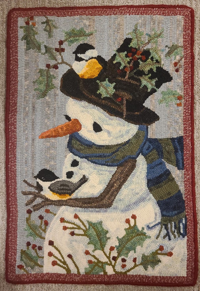 May include: A white snowman with a black hat and a blue and green scarf. The snowman is surrounded by green holly with red berries. Two small black and yellow birds are perched on branches.