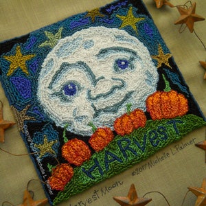 May include: A needlepoint design of a harvest moon with a smiling face and pumpkins. The text "Harvest Moon" is written below the moon and the text "Copyright 2017 Michelle L. Palmer" is written on the left side of the design.