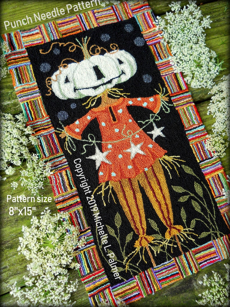 May include: Punch needle pattern of a pumpkin-headed scarecrow wearing a red and white polka dot dress and holding a string of stars. The pattern is framed with a colourful border and the text "Copyright 2019 Michelle L. Palmer" is visible in the lower right corner. The pattern size is 8" x 15".