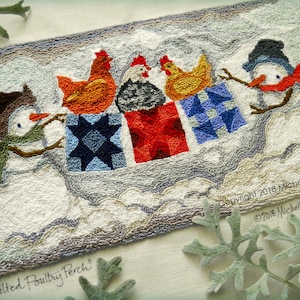 Op de afbeelding: Een handgestikt tapijt met sneeuwpoppen en kippen. De sneeuwpoppen houden cadeau dozen vast, en de kippen zitten erop. Het tapijt heeft een lichtgrijze en blauwe rand, met de tekst "Quilted Poultry Perch".