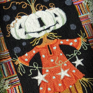 May include: A white pumpkin with a smiling face is dressed as a scarecrow with a red and white polka dot dress and straw-like hair. The scarecrow is holding a string of white stars. The background is a black and white checkered pattern with a colourful border. The text "Scarecrow season!" is at the top of the image. The text "Copyright Michelle L. Palmer" is at the bottom of the image.