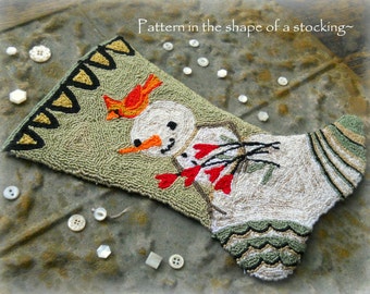 May include: Handmade Christmas stocking with a snowman and cardinal design. The stocking is green, white, and beige, with a snowman wearing a carrot nose and red scarf. The text "Pattern in the shape of a stocking" is visible.